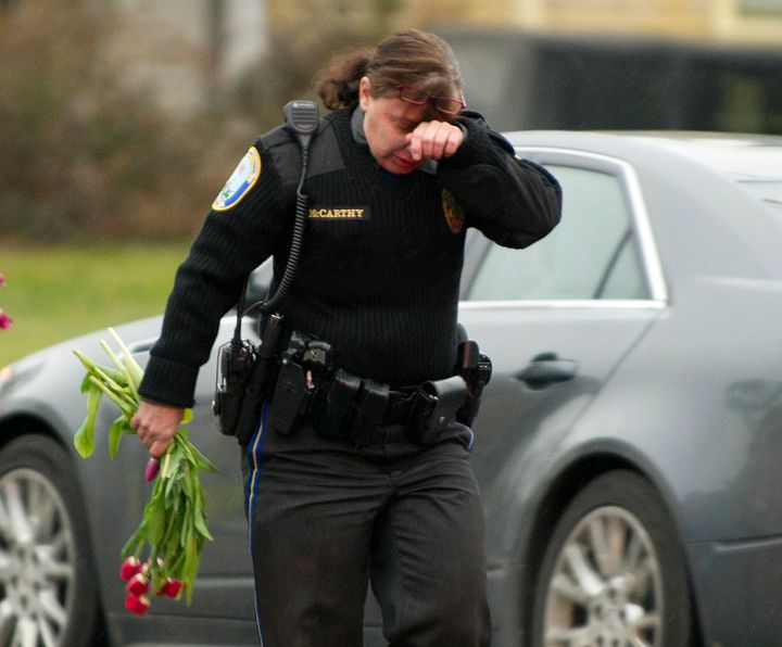 A police officer wipes her eyes as she removes flowers from a busy intersection December 16, 2012, in Newtown, Connecticut, on Dec. 16, 2012. Officers said a memorial left for the Sandy Hook Elementary school victims may have cause a traffic hazard.