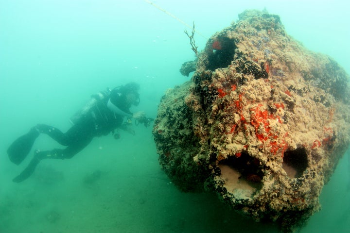 A diver with the UH Marine Option Program examines the gunner's forward turret on a PBY-5 Catalina resting on its right side