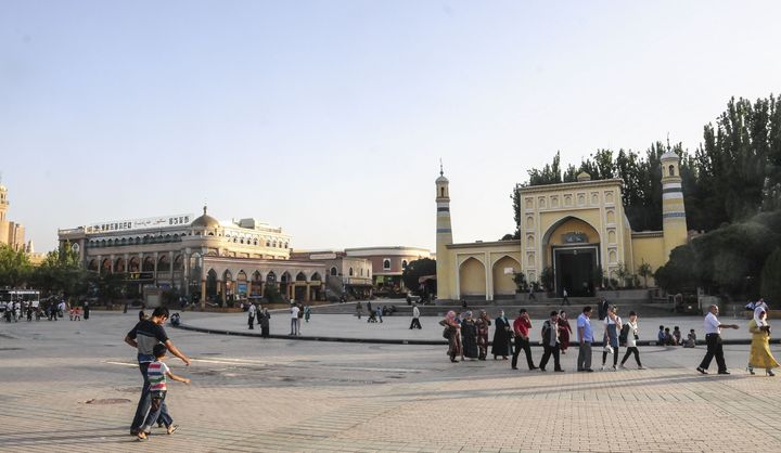 Uighur people walk outside the Id Kah Mosque in northwestern China's Xinjiang autonomous region on July 7, 2015.