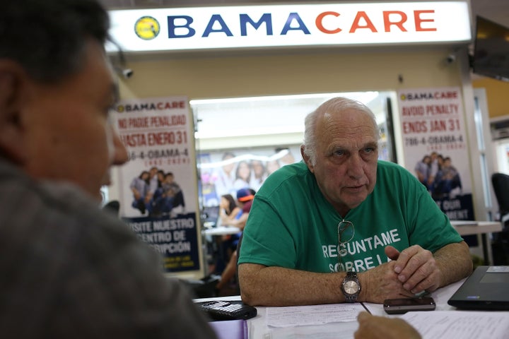 Insurance agent Antonio Galis, left, discusses health insurance plans with a client at the Mall of the Americas in Miami on Nov. 2.