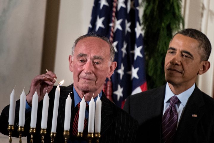 President Barack Obama watches as Martin Weiss, a Holocaust survivor, lights a menorah during a Hanukkah reception in the White House, Dec. 5, 2013.