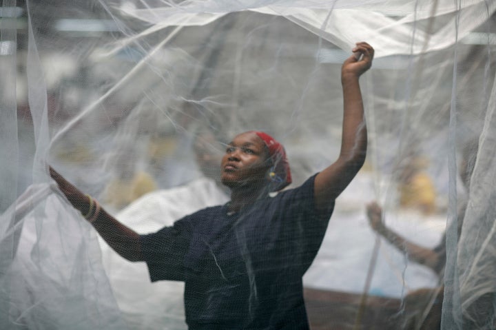 ARUSHA, TANZANIA - FEBRUARY 18: US President George W. Bush greets workers under a mosquito bed net during a tour of the A to Z Textile Mills on February 18, 2008 in Arusha, Tanzania. The company produces insecticidal bed nets, which help in the prevention of malaria. The company produces insecticidal bed nets which help in the prevention of malaria. The US president has used his visit -- which began in Benin on February 16, 2008, and will take him to Rwanda, Ghana and Liberia before he heads back to Washington -- to highlight US-African cooperation to battle disease and poverty.