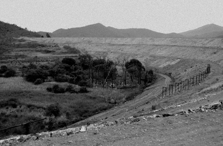 Researchers found that the Subarnarekha river and areas around Jadugoda, India, were poisoned from the emissions of a nearby secret nuclear factory. In this photo, villagers meet at a place of worship between two tailing dams in Jadugoda. The traditional holy trees are all dead due to high radiation levels.