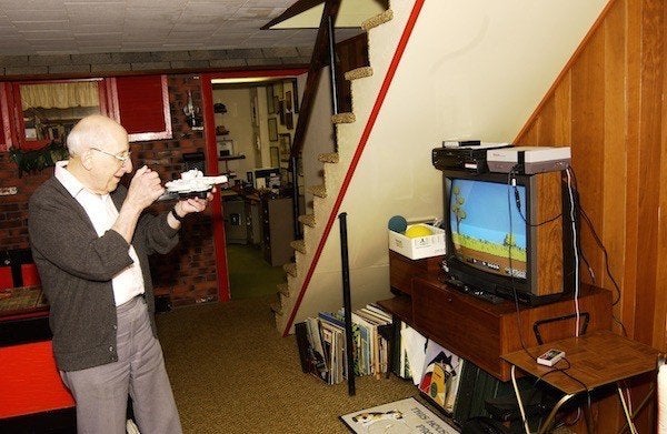 Baer playing a video game he invented; his basement workshop is in the background.