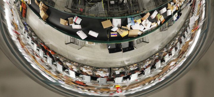 A mirror reflects packages moving along a conveyor belt at a USPS sorting facility in Scarborough, Maine. The Postal Service expects to deliver around 15 billion pieces of mail this holiday season.