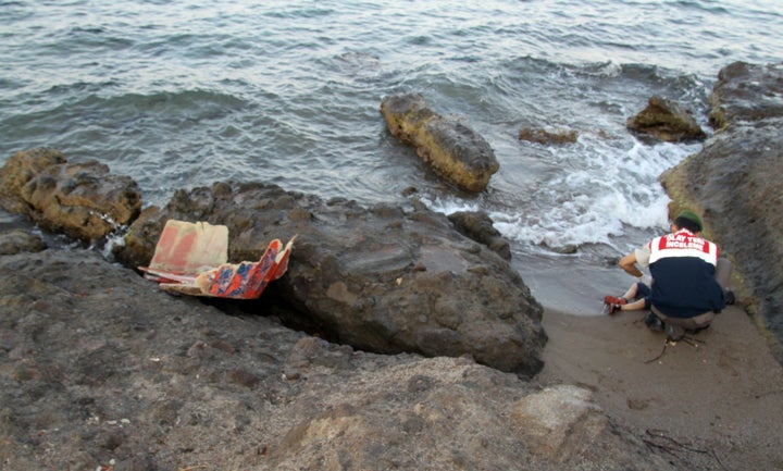 A Turkish gendarmerie soldier moves Alan Kurdi's body, which washed ashore on a beach after a boat carrying 12 migrants