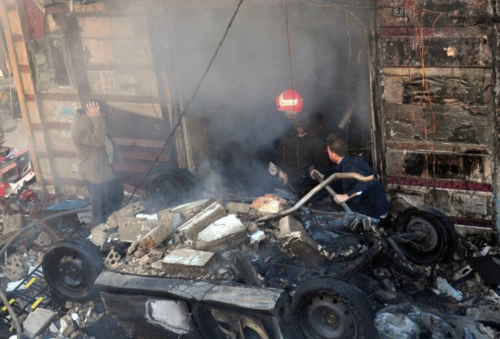 Emergency services extinguish a fire following two car bomb attacks in the al-Zahraa neighbourhood of the central Syrian city