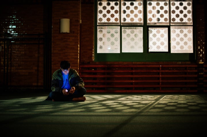 A refugee checks his cell phone at the prayer hall after arriving to Stockholm central mosque on Oct. 15, 2015.