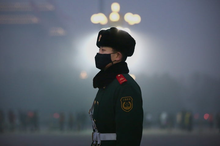 A Chinese paramilitary policeman wears a mask to protect against pollution as he guards during heavy pollution day in Tiananmen Square.