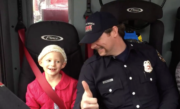 Finley Brown, 6, sits with firefighter Lucas Lambert in a fire truck as they head over to her last round of chemotherapy trea