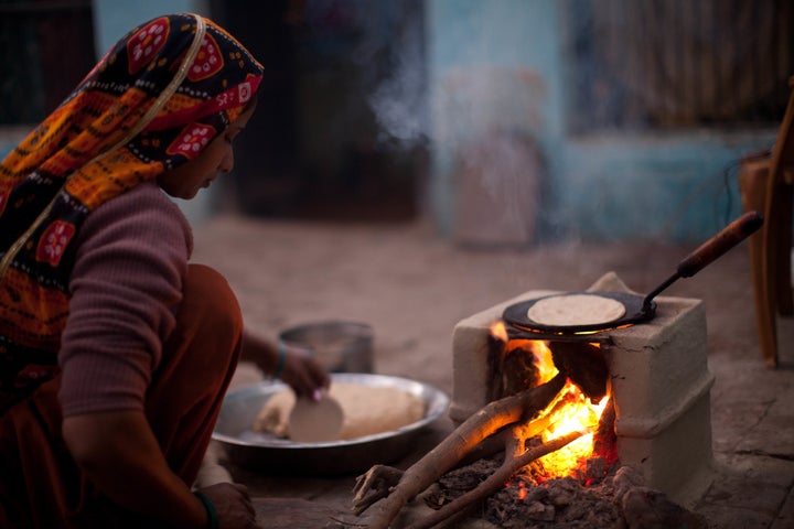 An Indian woman cooks over a traditional stove using wood and cow dung as fuel.