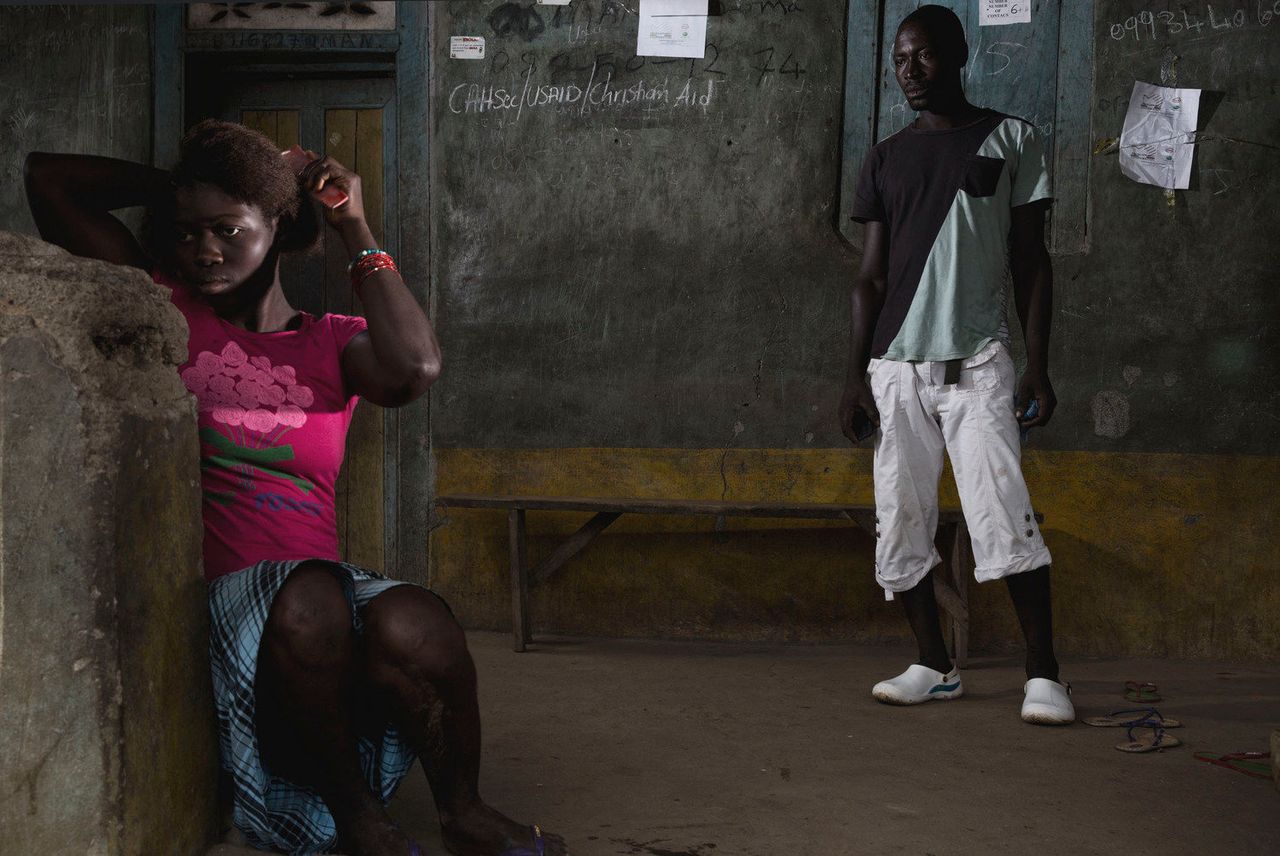 Ebola survivors Adam and Lamin stand in front of their home in Rosanda, where 16 people died from Ebola.