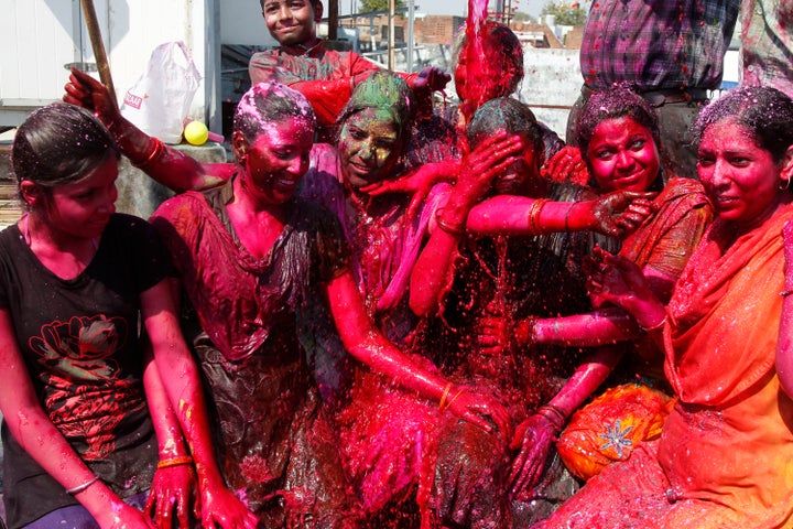 Women cover their body with colored powder as they celebrate the Holi festival in India.