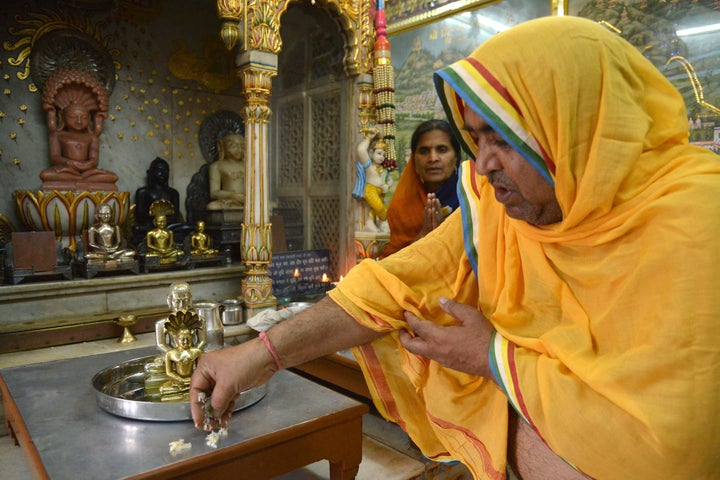 A Jain priest is watched by devotees as he offers prayers to idols of Lord Mahavir, on the occasion of Mahavir Jayanti at a temple in Amritsar, India.