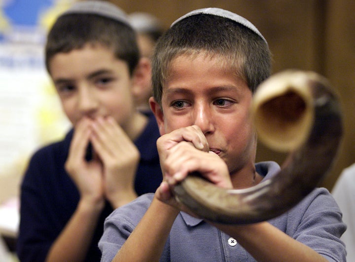 Third grader Ron Jacobs tries blowing the shofar, a rams horn, during a lesson on Rosh Hashanah in class.