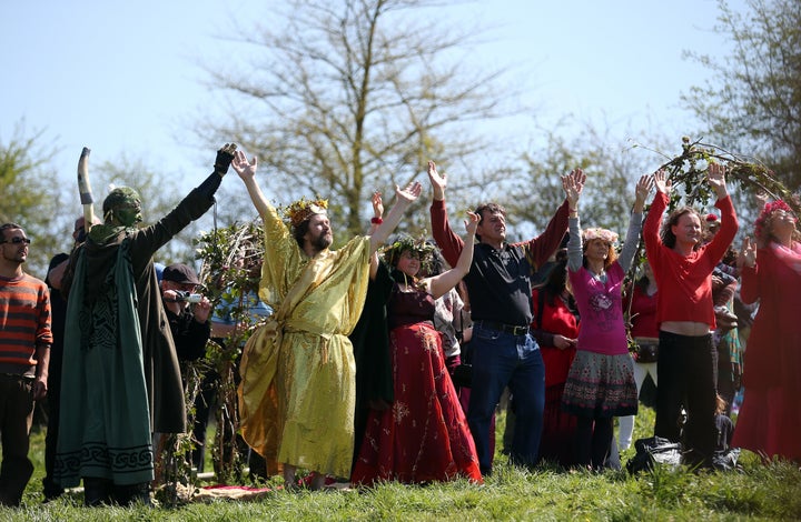 People raise their hands as they form a circle and take part in a Beltane May Day celebration below Glastonbury Tor in Glastonbury, England.