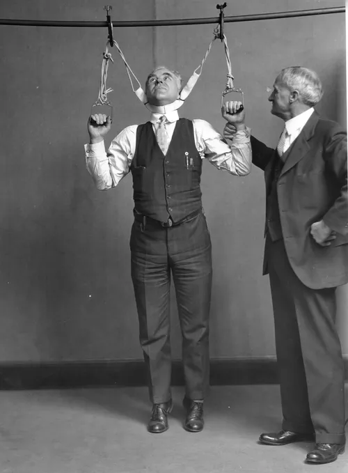Post Office Department Inspector DF Angier (left) and Dr. LF Kebler, formerly of the Food and Drug Administration, try out a stretching device which claimed to increase height by 2 to 6 inches, 1931.