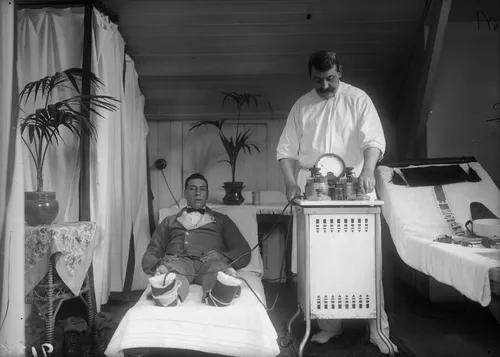A patient recuperating in the spa town of Harrogate is wired up to an electric machine used for the cure of frostbite and rheumatism, circa 1910.