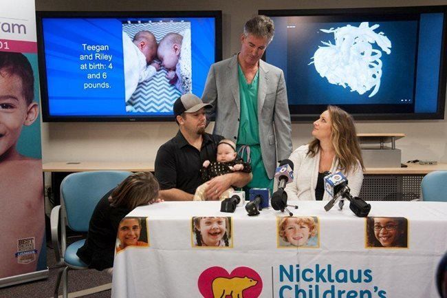 Dr. Burke stands with Cassidy and Chad Lexcen, parents of twins Teegan and Riley.