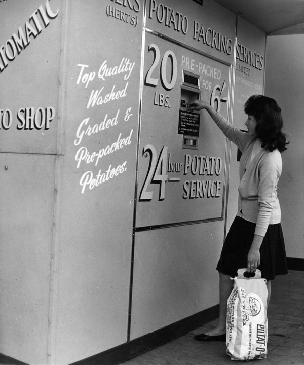 A Woman Operating The First Vending Machine In Britain To Sell Potatoes At Greengrocers Shop A Woman Operating The First Vending Machine In Britain To Sell Potatoes At Greengrocers Shop