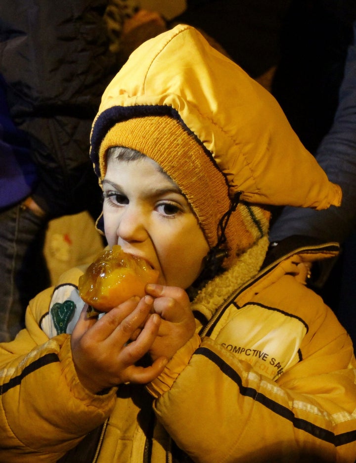 A Syrian child eats a fruit on the outskirts of the besieged rebel-held Syrian town of Madaya, on January 11, 2016, after bei