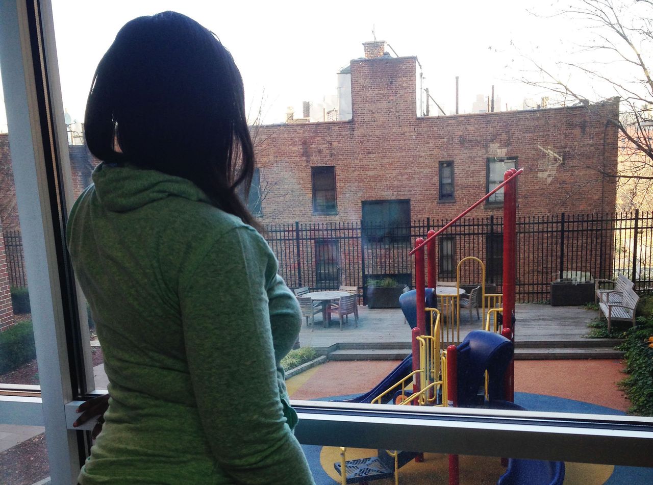 A once-homeless domestic violence survivor looks out the window of her apartment building.