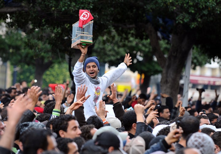 A Tunisian demonstrator holds a cage and the national country flag during a rally on Jan. 14, 2011, outside the Interior Ministry in Tunis, demanding the resignation of Ben Ali.