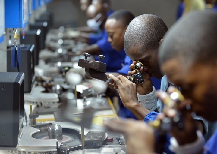 Workers check, cut and polish diamonds at a Diamond cutting and polishing company during the tour by Ghanian President John D