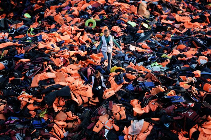 A woman is dwarfed by a mountain of life jackets that refugees and migrants left behind on the Greek island of Lesbos. Now, volunteers are finding a way to put the life jackets to good use.