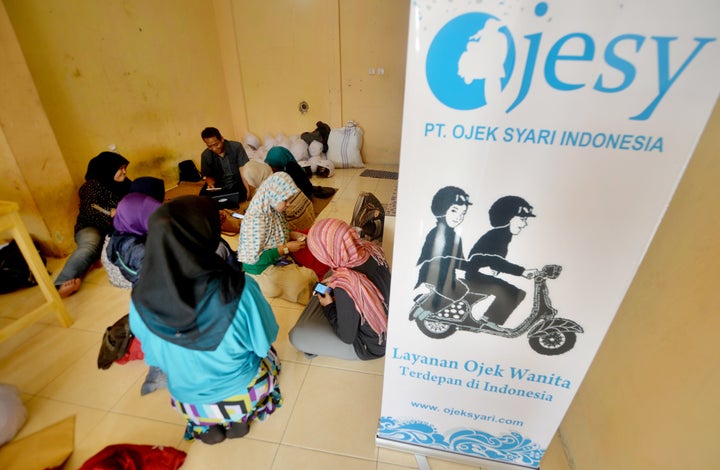 Female motorbike taxi drivers are seen learning how to take orders from their smartphones at an office in Jakarta.