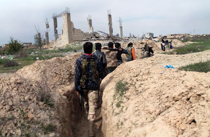 The self-described Islamic State released 270 out of an estimated 400 civilians kidnapped over the weekend in the government-held city of Deir al-Zor, Syria. People fighting against the Syrian government walk along a trench in the city.