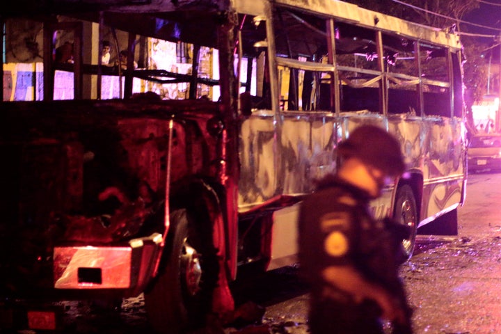 A police officer stands next to a burned bus in Acapulco, Mexico. The famous resort town is now the city with Mexico's highest homicide rate.