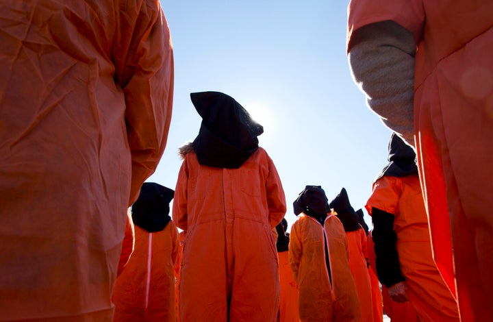 Protesters wearing orange jumpsuits depicting Guantanamo Bay detainees participate in a rally outside of the White House