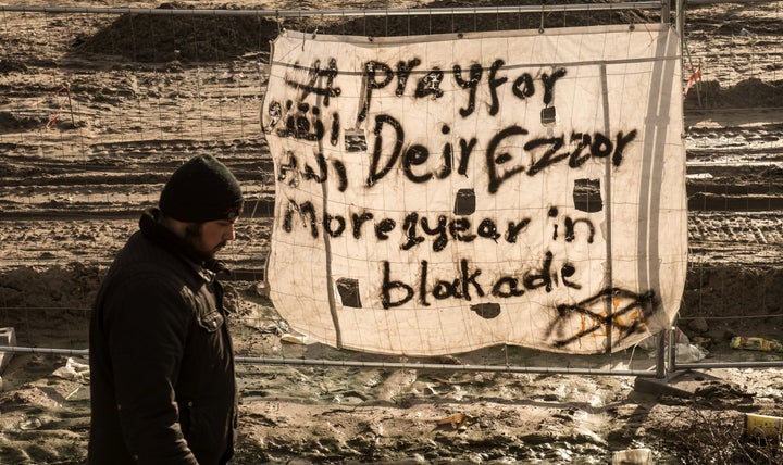 A man walks past a banner reading "Pray for Deir Ezzor" at a camp in December, 2015. Although Islamic State militan