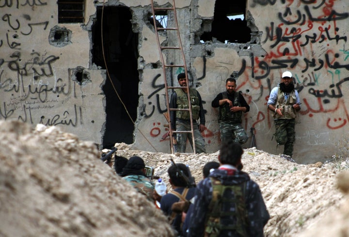 Fighters walk along a trench in Deir Ezzor. The Islamic State group blocks food from entering the town's neighborhoods,