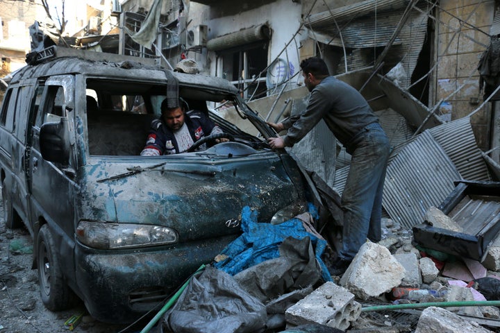 People inspect a damaged vehicle following a reported air strike by government forces on Aleppo, Syria. Deir Ezzor