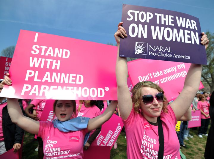 Participants display signs at a rally to "stand up for women's health" at the National Mall in Washington, DC, in April 2011. A new study suggests men lead media coverage focused on reproductive issues.