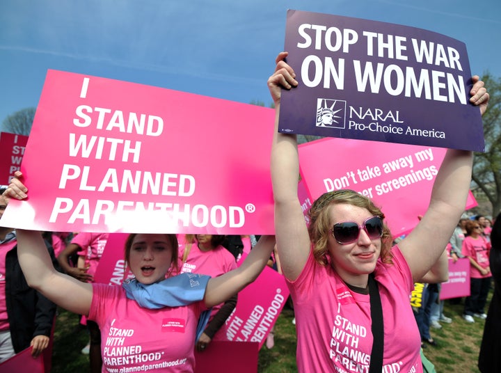 Participants display signs at a rally to "stand up for women's health" at the National Mall in Washington, DC, in April 2011. A new study suggests men lead media coverage focused on reproductive issues.