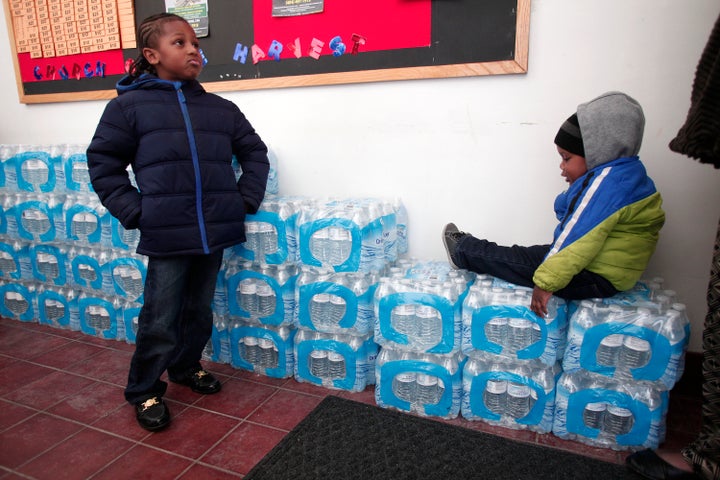 Flint residents Justin Roberson, age 6, and Mychal Adams, age 1, of Flint wait on a stack of bottled water at a rally where the Rev. Jesse Jackson was speaking about about the water crises at the Heavenly Host Baptist Church.