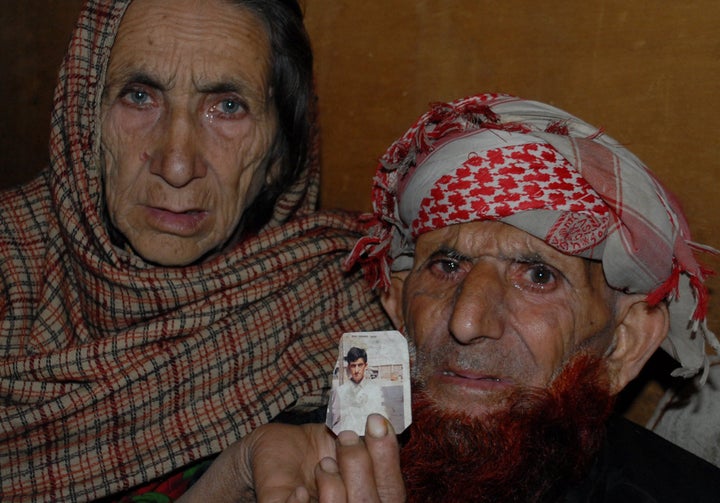 The parents of Shafqat Hussain, a Pakistani convicted of murder at age 14, hold a photograph of their son in Muzaffarabad, th