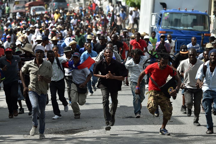 Demonstrators run during a protest in Port-au-Prince, on January 22, 2016.