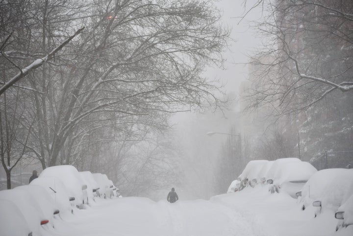 A pedestrian walks in the center of a snow-covered residential street in Washington, DC, on Saturday.