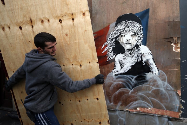 Builders cover a Banksy artwork shortly before being told to take it down from the building opposite the French embassy on January 25, 2016, in London, England.