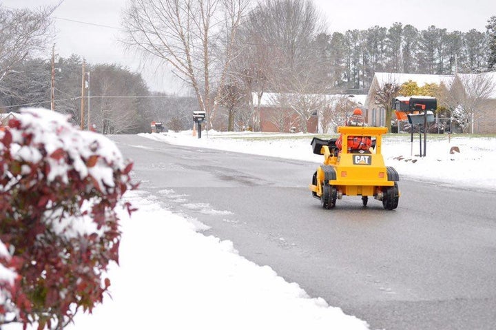 Sam riding down the street in his bulldozer. 