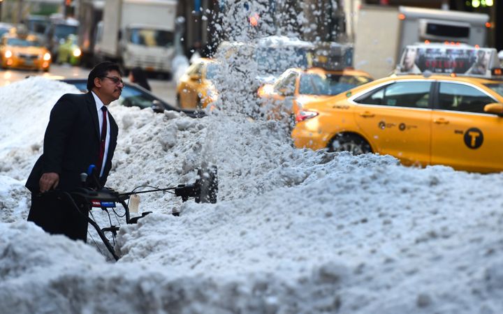 A worker clears snow on Third Avenue in New York City on Jan. 25, 2016, as New Yorkers return to work after a record-setting snowfall.