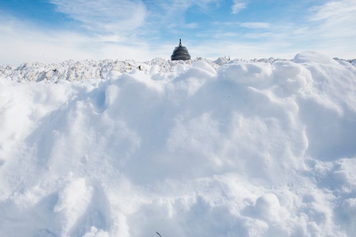 The dome of the U.S. Capitol building peeks above mounds of snow piled by the Capitol Reflecting Pool on Jan. 25, 2016.