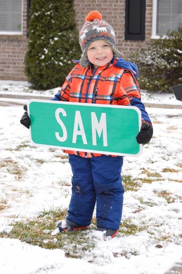 Sam holding a street sign with his name. 