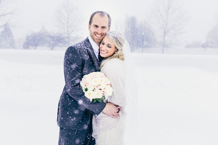 The bride and groom sharing a sweet, snowy embrace.