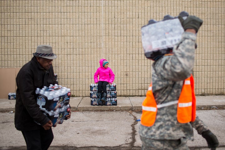 National Guard members and civilians carry cases of water to residents in Flint, Michigan, on Jan. 23.