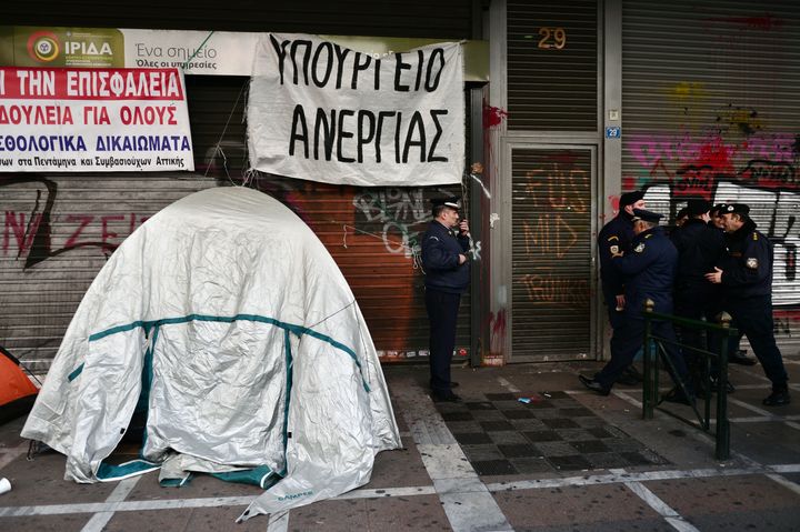 Even before the financial crisis brought about budget cuts and austerity measures, Greece was among a group of countries with a fertility rate of 1.5. Above, police stand outside the labor ministry in Athens where a banner reads "Ministry of Unemployment" on Dec. 17, 2015.